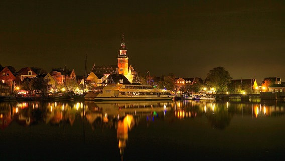 Der beleuchtete Museumshafen in Leer (Ostfriesland) spiegelt sich bei Dunkelheit auf der Wasseroberfläche. © NDR Foto: Erich van der Wall