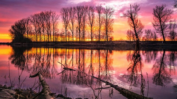 Ein bunter Morgenhimmel spiegelt sich in der Weser bei Nienburg, kurz vor dem Sonnenaufgang. © NDR Foto: Christian Ravenstein