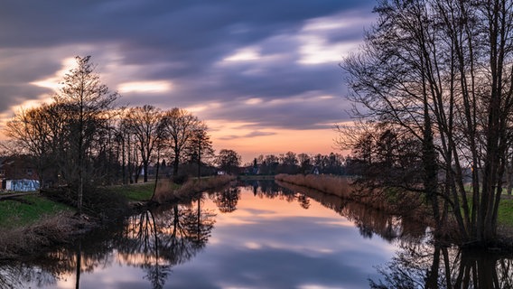 Hinter lilafarbenen Wolken geht die Sonne an der Hunte im Landkreis Oldenburg unter. © NDR Foto: Wencke Iburg