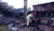 Ein Feuerwehrman begutachtet einen abgebrannte Boothalle in Wilhelmshaven. © TeleNewsNetwork 
