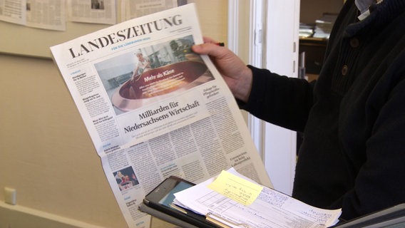 Ein Mann hält eine Ausgabe der Lüneburger Landeszeitung in der Hand. © NDR 