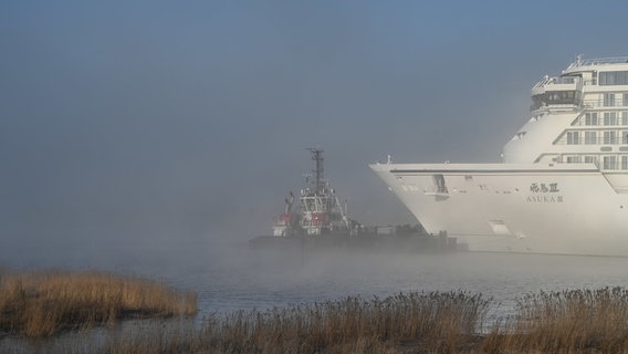 Ein Schlepper zieht das neue Kreuzfahrtschiff der Meyer Werft, die "Asuka III", die Ems entlang. © dpa Bildfunk Foto: Lars Penning