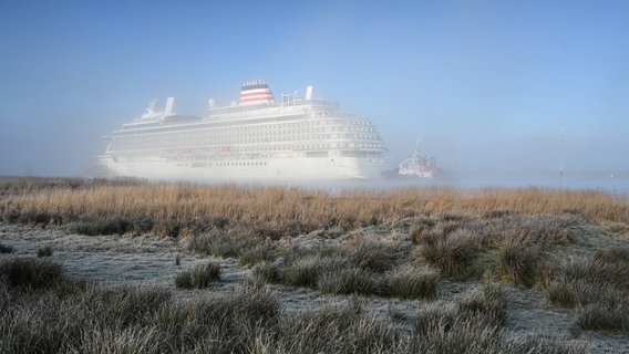 Ein Schlepper zieht das neue Kreuzfahrtschiff der Meyer Werft, die "Asuka III", die Ems entlang. An Land ist Frost zu sehen. © dpa Bildfunk Foto: Lars Penning