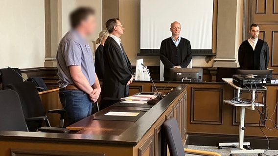 Ein Angeklagter steht in einem Gerichtssaal. © NDR Foto: Maren Momsen