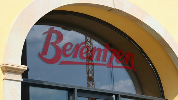 Ein Fenster mit dem roten Schriftzug des Unternehmens "Berentzen". Im Fenster spiegelt sich ein Baukran. © NDR Foto: Susanne Schäfer