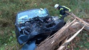 Ein Feuerwehrmann an einem Auto und einem abgebrochenen Baum nach einem Unfall in Bersenbrück © Nord-West-Media TV 