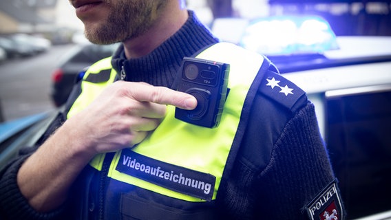 Ein Polizist startet mit einem Finger eine Bodycam. © dpa-Bildfunk Foto: Friso Gentsch