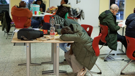 Einige Betroffene schlafen zusammengekauert auf einem Tisch im Evakuierungszentrum der Stadt in einer Schule. © dpa Foto: Friso Gentsch