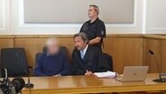 Ein Angeklagter sitzt neben seinem Verteidiger in einem Gerichtssaal. © NDR Foto: Susanne Schäfer