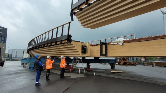 Eine Holzbrücke wird für einen Testaufbau mit einem Kran zusammengesetzt. © NDR Foto: Britta Nareyka