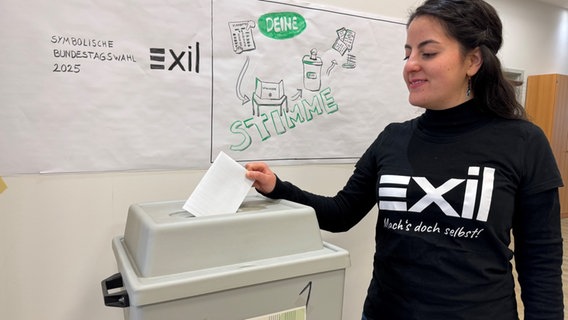 Eine junge Frau steckt einen Zettel in eine Wahlurne bei einer symbolischen Bundestagswahl in Osnabrück. © Exil e.V. Foto: Marlene Schriever