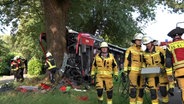 Zahlreiche Einsatzkräfte stehen vor einem Bus der in Bad Bentheim gegen einen Baum geprallt ist. © NWM-TV 