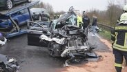 Ein Pkw steht völlig zerstört auf einer Straße neben einem Autotransporter. © Nord-West-Media TV 