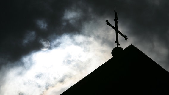 Das Kreuz einer Kirche vor wolkenverhangenem Himmel. © dpa Bildfunk Foto: Friso Gentsch