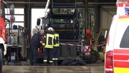 Einsatzkräfte der Polizei und Feuerwehr sichern den Unfallort um die Landmaschine ab. © NDR 