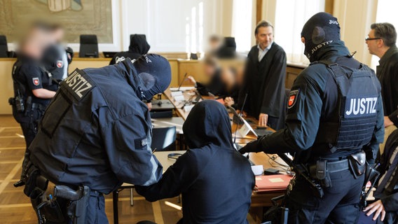 Ein Angeklagter (M) wird von Spezialkräften der Polizei in einen Saal vom Landgericht Osnabrück begleitet beim Prozess gegen sieben mutmaßliche Geldautomatensprenger. © dpa-Bildfunk Foto: Friso Gentsch