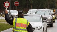 Ein Beamter der Bundespolizei leitet am 1. Juli 2017 den Einreiseverkehr aus den Niederlanden auf der A30 bei Bad Bentheim (Niedersachsen) zur Kontrolle über einen Parkplatz. © picture alliance / Ingo Wagner/dpa Foto: Ingo Wagner