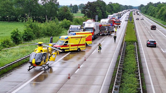 Ein Hubschrauber, zwei Rettungswagen und zwei Fahrzeuge der Feuerwehr stehen nach einem Unfall mit mehreren Lkw auf der A1 bei Groß Ippener. © Nord-West-Media TV 