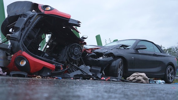 Das Wrack eines Leichtkraftfahrzeug liegt seitlich auf einer Straße. Ein zweites Auto steht demoliert davor. © NordWestMedia 