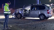 Ein Polizist steht nach einem Unfall neben einem Auto bei Meppen. © Nord-West-Media TV 