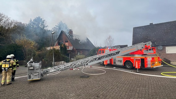 Feuerwehrleute stehen vor einem brennenden Einfamilienhaus in Meppen. © Nord-West-Media TV 