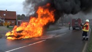 EInsatzkräfte der Feuerwehr löschen einen brennenden Pkw. © Nord-West-Media TV 