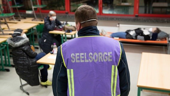 Ein Seelsorger steht in einem Klassenzimmer, in dem sich mehrere Menschen befinden. © dpa-Bildfunk Foto: Friso Gentsch