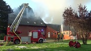 Feuerwehrleute löschen unter Zuhilfenahme einer Drehleiter ein Gebäude auf dem Gelände eines landwirtschaftlichen Betriebes in Papenburg. © Nord-West-Media TV 