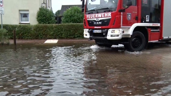 Eine Feuerwehr fährt in eine nach starken Regenfällen überflutete Straße in Quakenbrück. © Nord-West-Media TV 