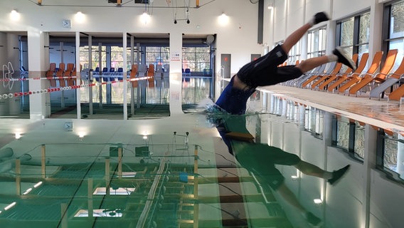 Ein Mann springt kopfüber in ein Schwimmbecken. © NDR Foto: Britta Nareyka