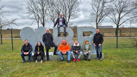 Mehrere Menschen stehen und sitzen rund um eine Skulptur, die aus einem großen Herzen und den Buchstaben B und R besteht. © Stadt Bramsche Foto: Stadt Bramsche