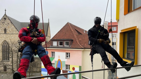 Als Superhelden verkleidete Feuerwehrleute seilen sich am Kinderkrankenhaus in Osnabrück ab. © NDR Foto: Andreas Gervelmeyer