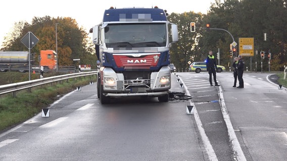 Polizeibeamte stehen nach einem tödlichen Unfall neben einem Lkw und einem Fahrrad auf einer Straße. © Nord-West-Media 