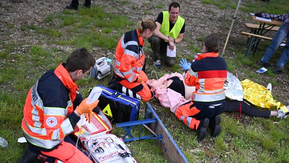 Einsatzkräfte versorgen Verwundete auf einer Wiese. © dpa-Bildfunk Foto: Lars Penning/dpa