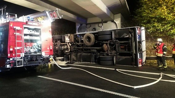 Unter einer Autobahnbrücke liegt ein verunfallter Lkw, daneben ein Einsatzfahrzeug der Feuerwehr. © NordwestMedia TV 