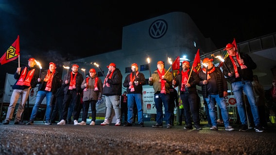 Warnstreik: Mitarbeiter von Volkswagen stehen mit Fackeln vor dem VW Werk in Osnabrück. © dpa 