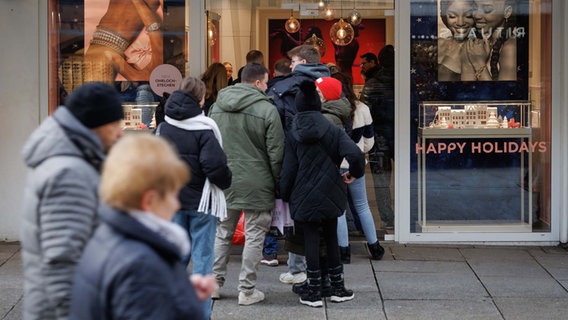 Menschen stehen einen Tag vor Heiligabend vor einem Schmuckgeschäft in Osnabrück Schlange. © dpa Foto: Friso Gentsch