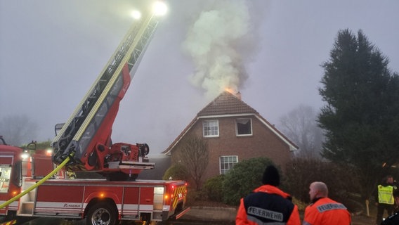 In Oxstedt steht ein Einfamilienhaus in Flammen. Der Rauch steigt aus dem Gebäude. Die Feuerwehr steht mit einer Drehleiter davor. © Polizeiinspektion Cuxhaven Foto: Pressestelle Polizei Cuxhaven