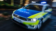 Ein mit Bewegungsunschärfe abgelichtetes Polizeiauto fährt mit Blaulicht eine Straße entlang. © NDR Foto: Julius Matuschik