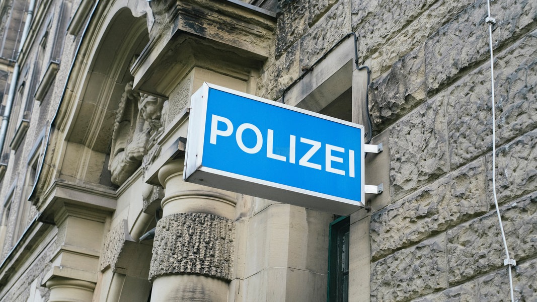 An einer Hausfassade hängt ein Leuchtschild mit der Aufschrift Polizei.