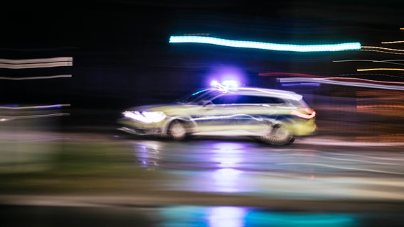 Ein Streifenwagen fährt bei Dunkelheit mit eingeschaltetem Blaulicht. © NDR Foto: Julius Matuschik