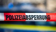 Ein Absperrband mit der Aufschrift «Polizeiabsperrung» ist vor einem Polizeiwagen aufgespannt. © dpa-Bildfunk Foto: David Inderlied