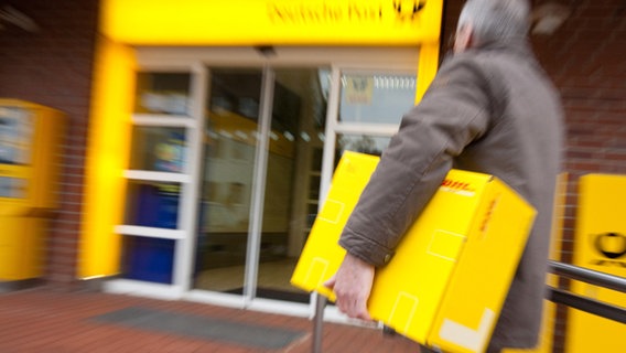 Ein Mann bringt ein Paket in eine Postfiliale. © dpa Foto: Kai Remmers