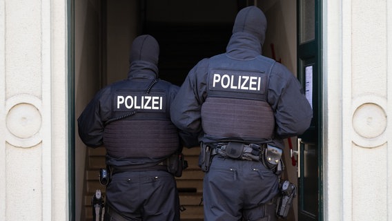 Polizisten stehen während einer Razzia in einer Haustür. (Symbolbild) © picture alliance/dpa Foto: Sebastian Kahnert