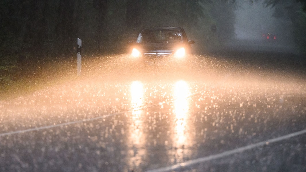 Ein Auto fährt während eines Gewitters mit Starkregen über eine Landstraße in der Region Hannover.