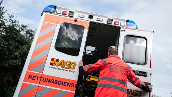 Ein Rettungssanitäter des Arbeiter-Samariter-Bund (ASB) schließt die Ladetüren an einem Rettungswagen. © NDR Foto: Julius Matuschik