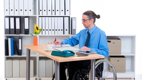 Ein Mann sitzt im Rollstuhl am Schreibtisch © picture alliance Foto: Marko Volkmar