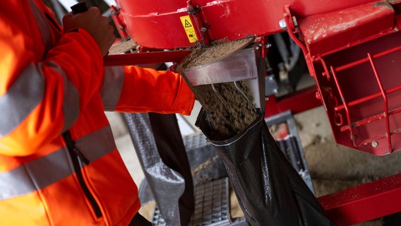 Ein Sandsack wird mithilfe einer Maschine befüllt. © picture alliance/dpa | Lennart Preiss Foto: Lennart Preiss