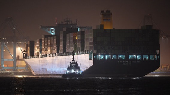 Ein großer MSC Frachter im dunkeln, vorne ein Schlepper. © NDR 