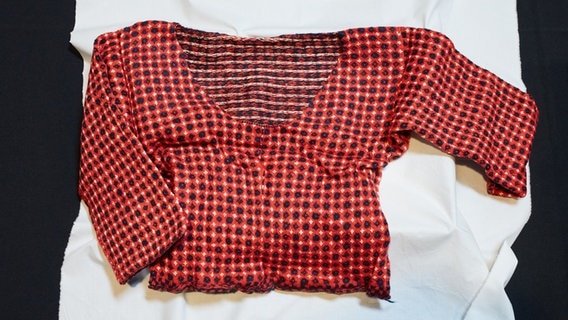 Ein Strickpullover aus einem 200 Jahre alten versiegelten Paket liegt auf einem weißen Tuch. © dpa-Bildfunk Foto: Maria Cardamone/Prize Papers Project